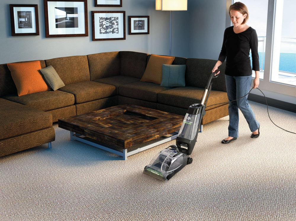 Positive black couple cleaning up together, vacuuming under carpet